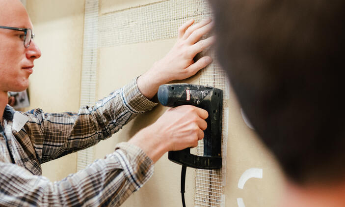 Ein Handwerker bei der Arbeit an Lehmplaten